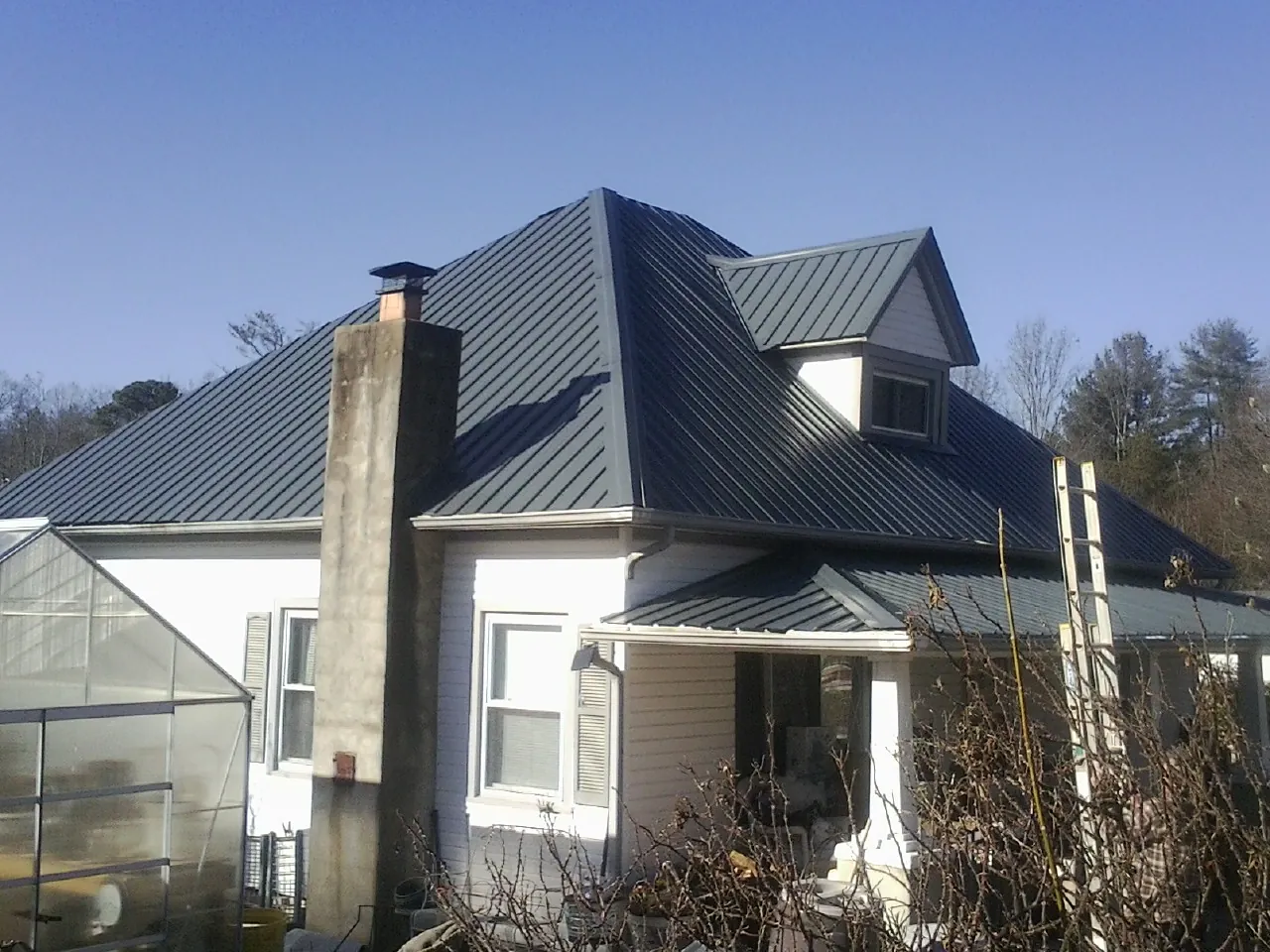 Dark blue standing seam metal roof on a white farmhouse with dormer — Slate & Tile Roof Repair by Roofing Brothers in West Simsbury