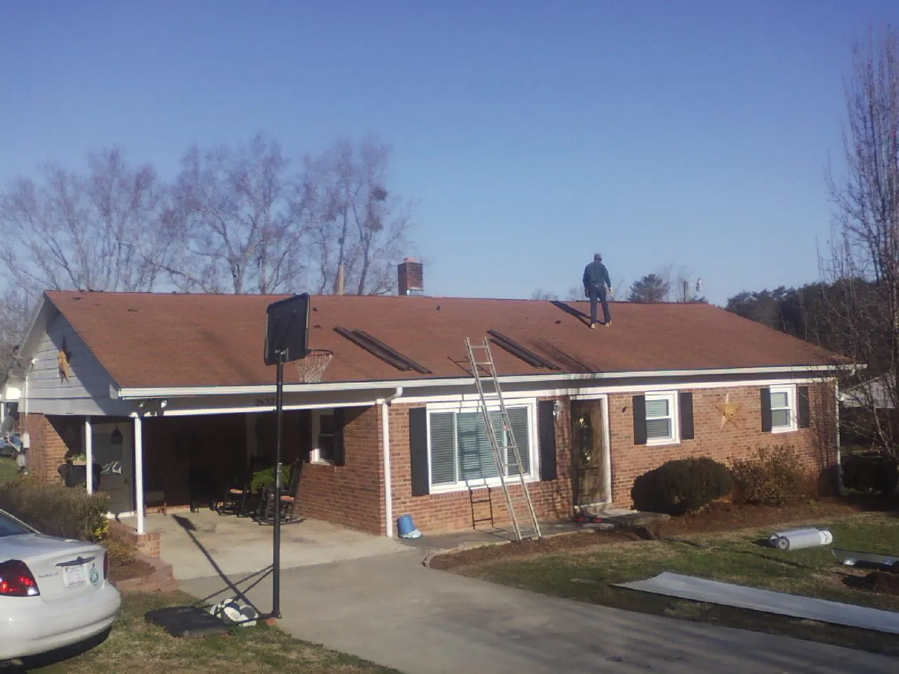 Roofer stripping a shingle roof on a brick ranch before metal panels in West Simsbury