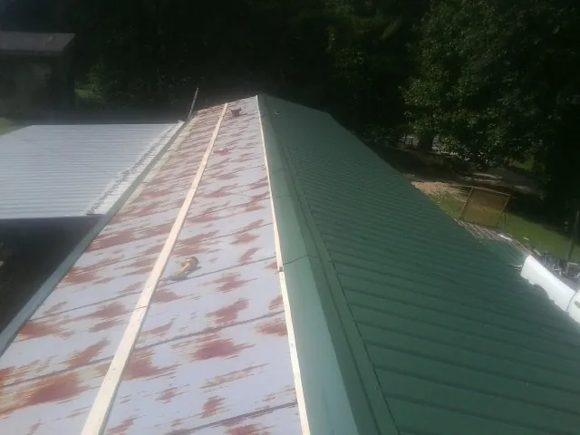 Old rusted panels beside newly installed green metal roofing — Wind Damage Roof Repair by Roofing Brothers in West Simsbury
