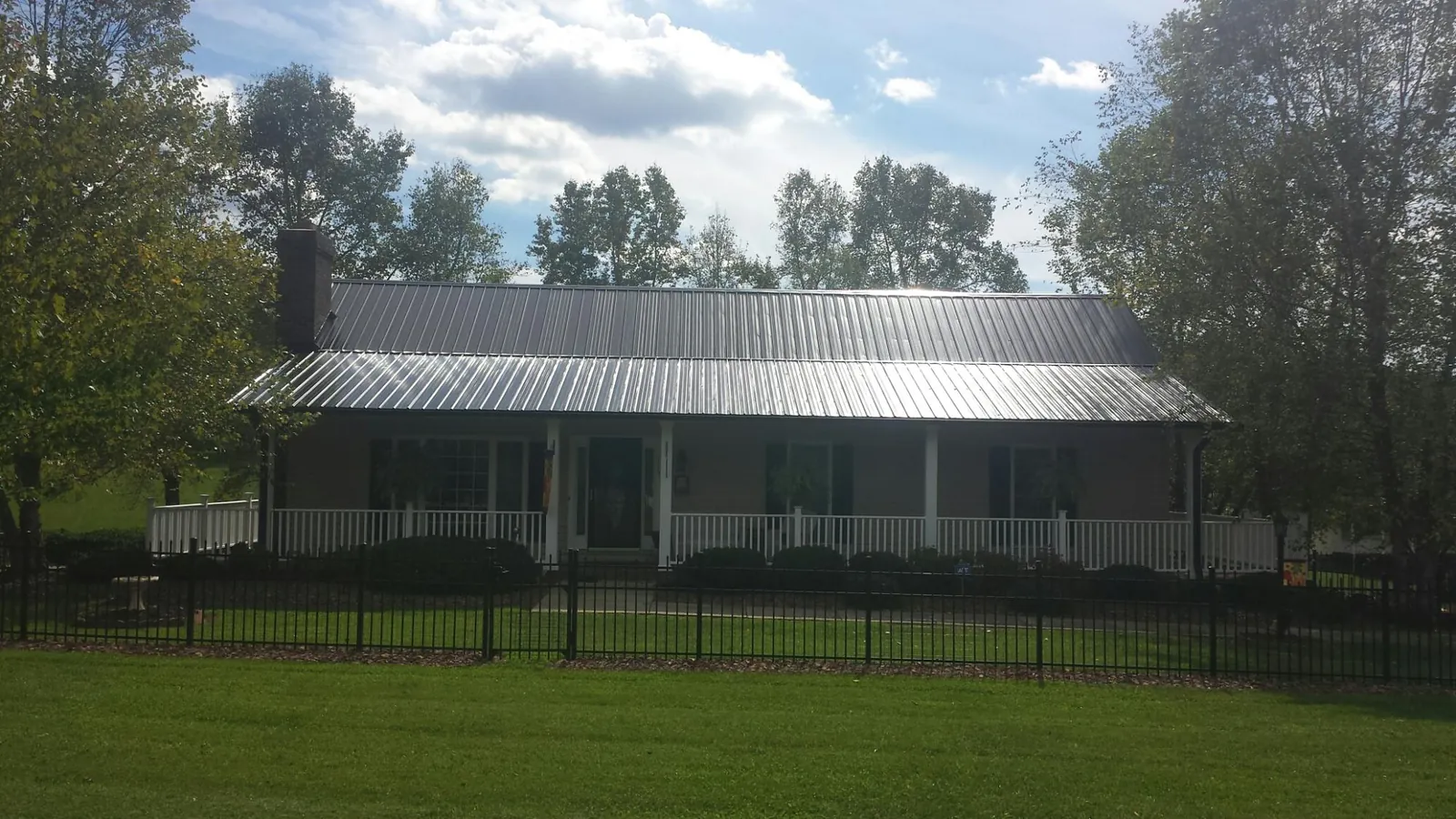 Gray metal roof on a brick ranch with a full width front porch — Gutter Guard Installation work by our crew in West Simsbury