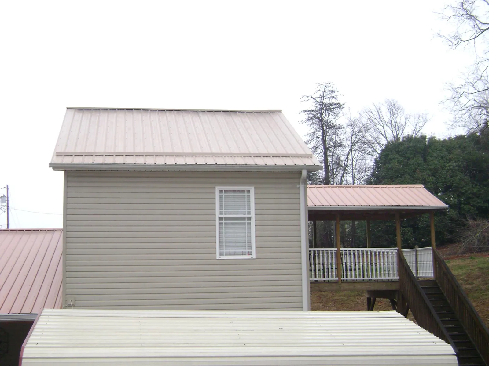 Tan metal roofs on a two story addition and attached porch, from a Roof Replacement job in West Simsbury