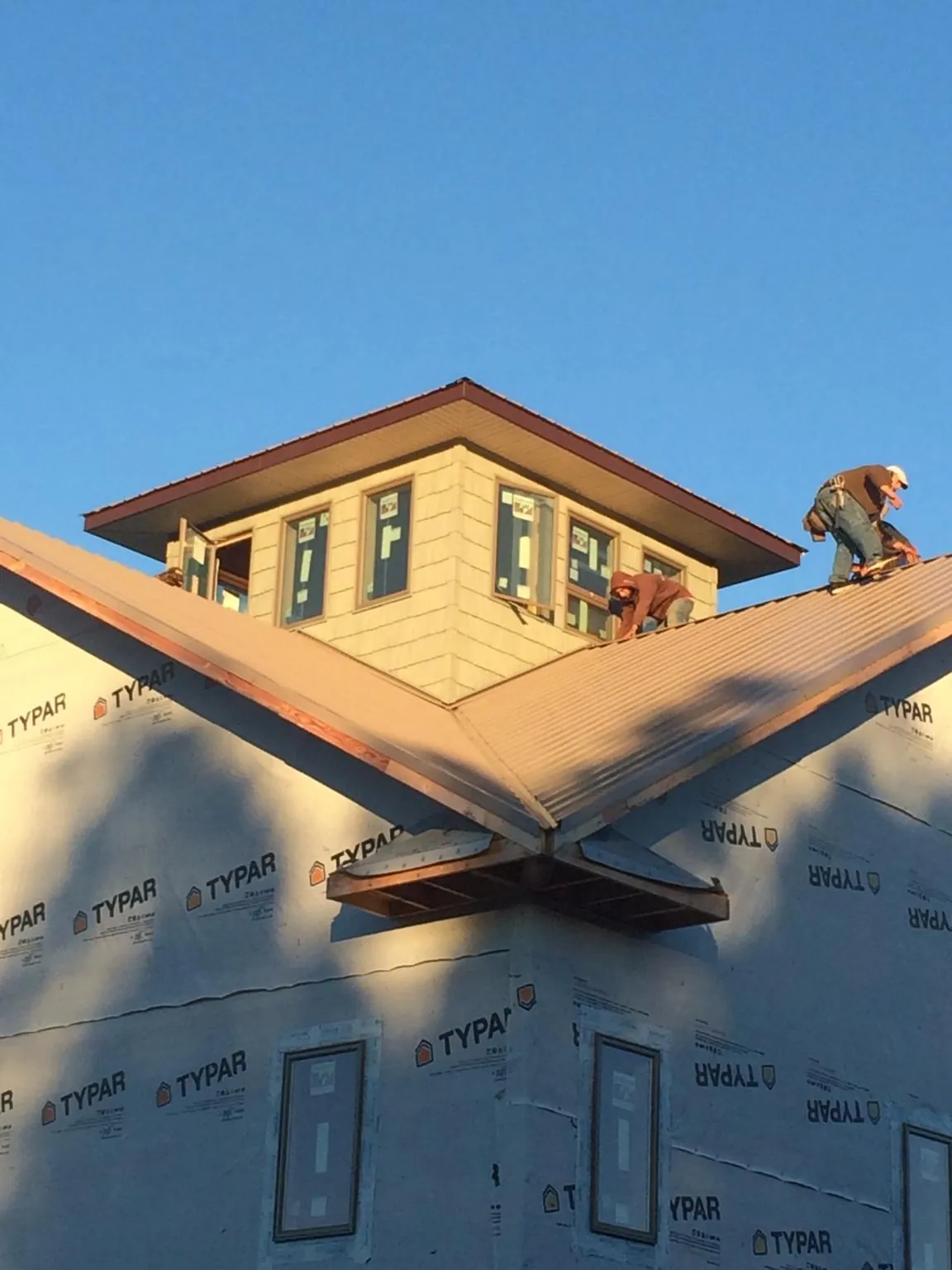 Roofers working around a rooftop cupola on a new metal roof at sunset — Roof Waterproofing in West Simsbury by Roofing Brothers
